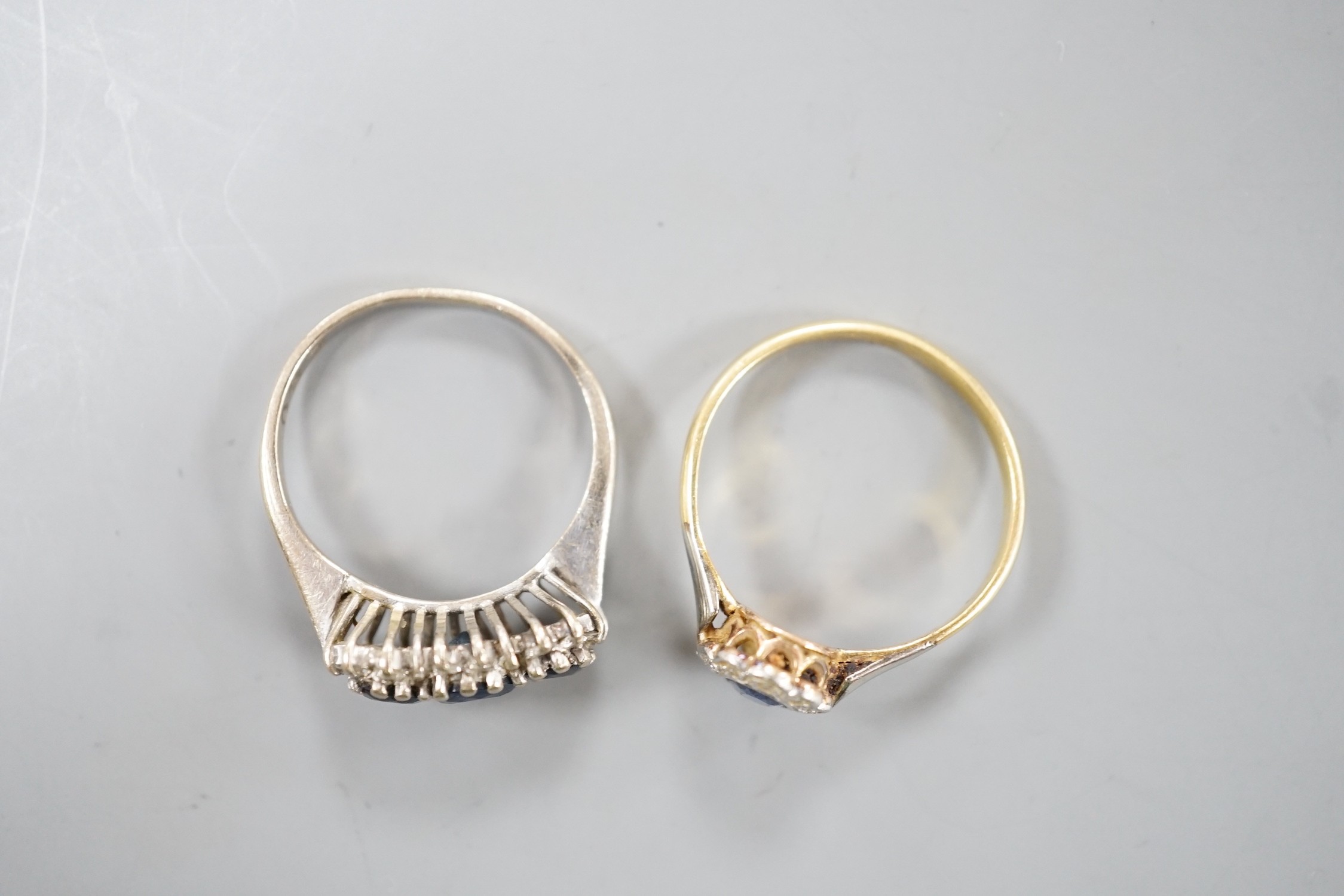An 18ct white metal, sapphire and diamond set triple cluster ring, size O and a yellow metal, sapphire and diamond set oval cluster ring, size O/P, gross weight 6.8 grams.